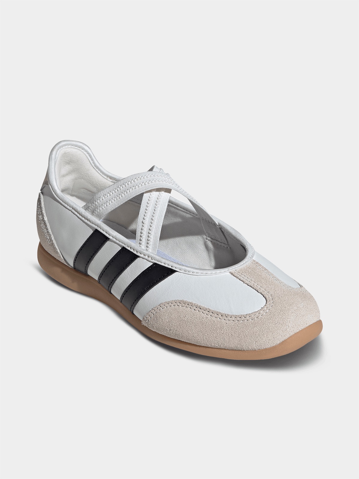 Three-quarter view of the white and black Adidas mary-jane sneaker on a plain background, showing the crossover strap detail across the instep