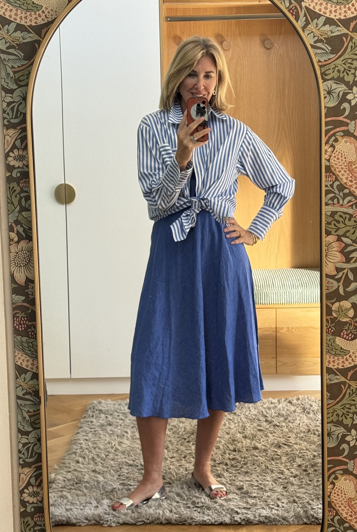 Julie wearing the blue and white thin-stripe boyfriend shirt tied at the waist over the blue linen Thea shift dress