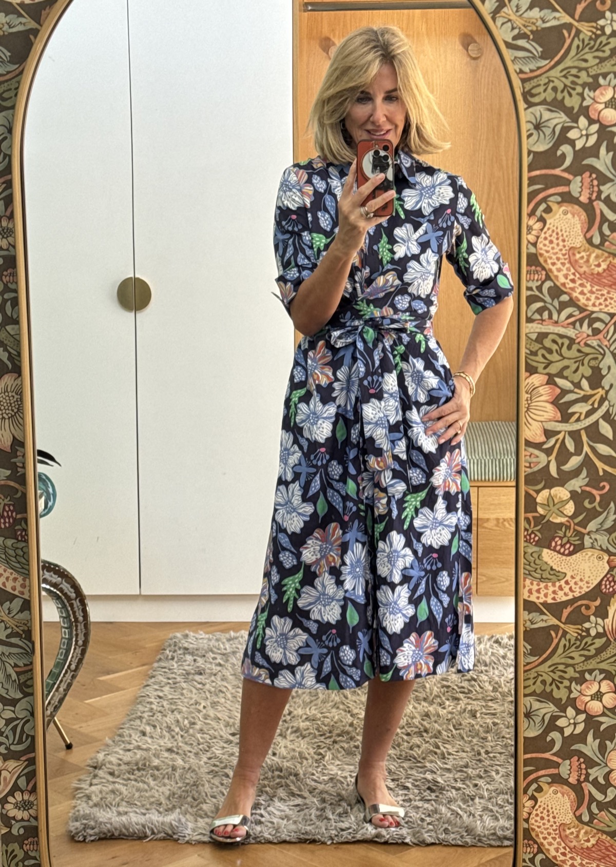 Julie wearing the Cath shirt dress in a navy, blue and white floral print, waist tied, styled with metallic sandals