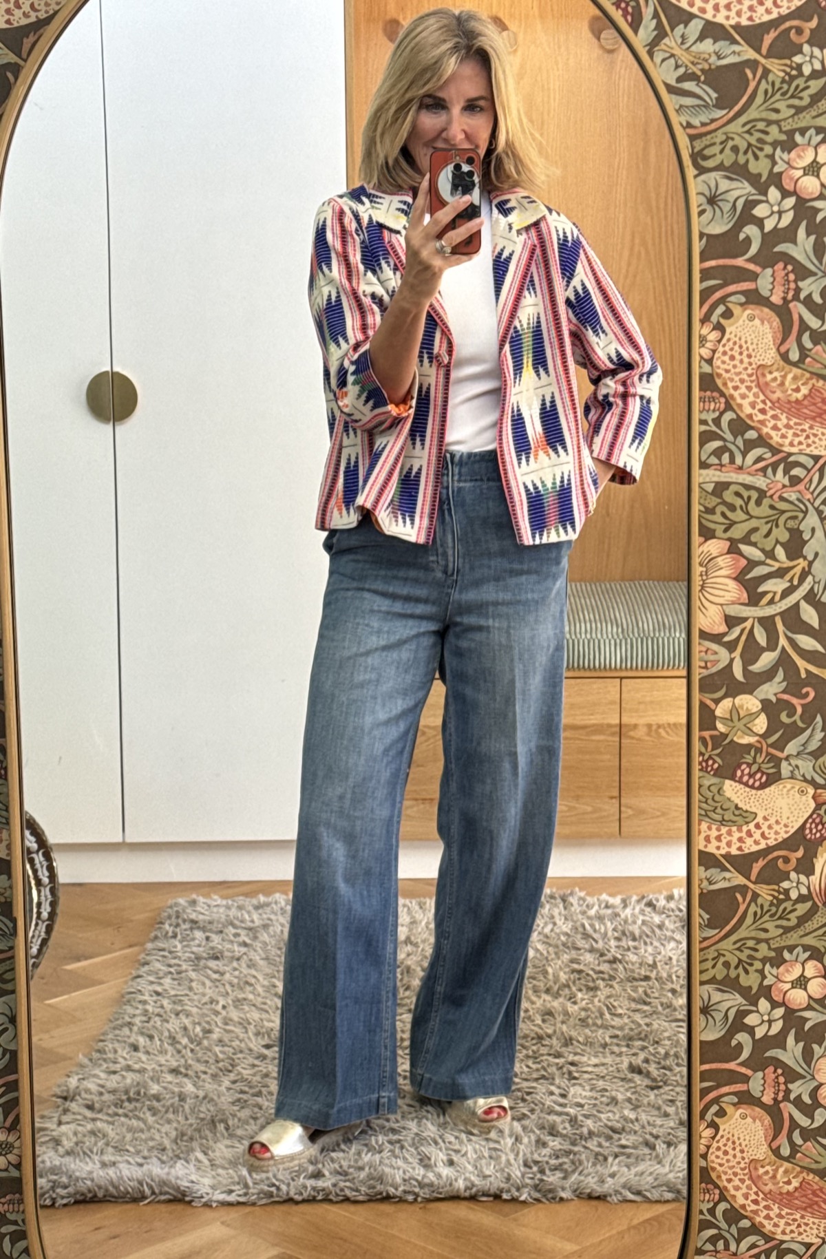 Julie wearing the Delphine jacket in a blue, cream and multicolour ikat weave, open over a white top and wide-leg blue jeans