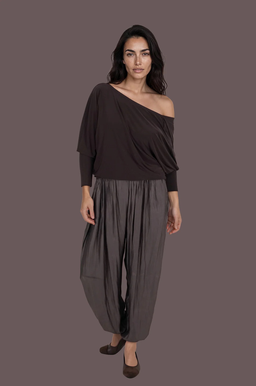 Woman wearing an off-shoulder brown top with mocha-brown drapey satin balloon pants and heels