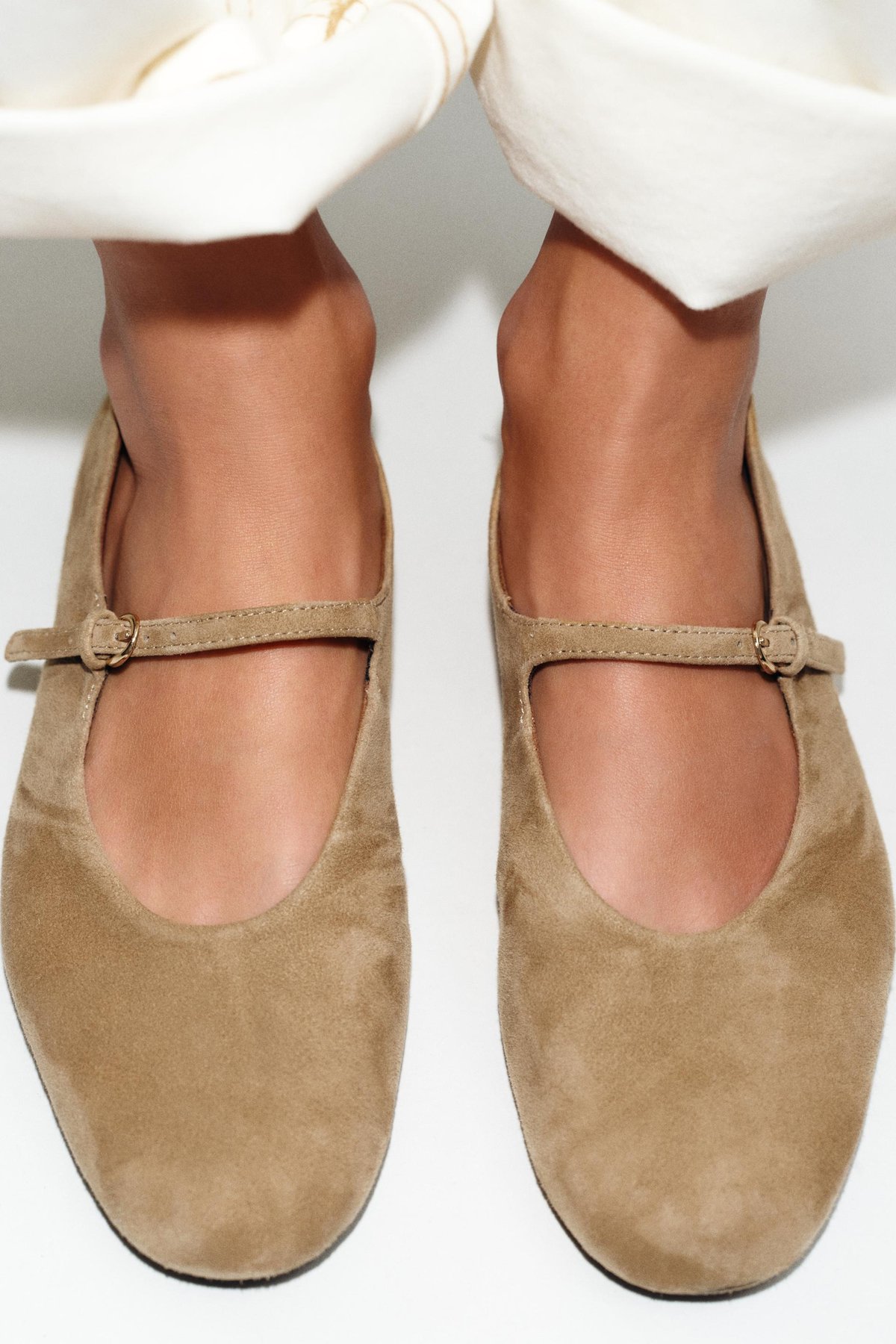 A pair of taupe suede Mary Jane-strap ballet flats, angled product shot against a plain light background.