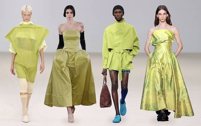 Four runway looks in bold chartreuse green, including a draped gown and a belted jacket.