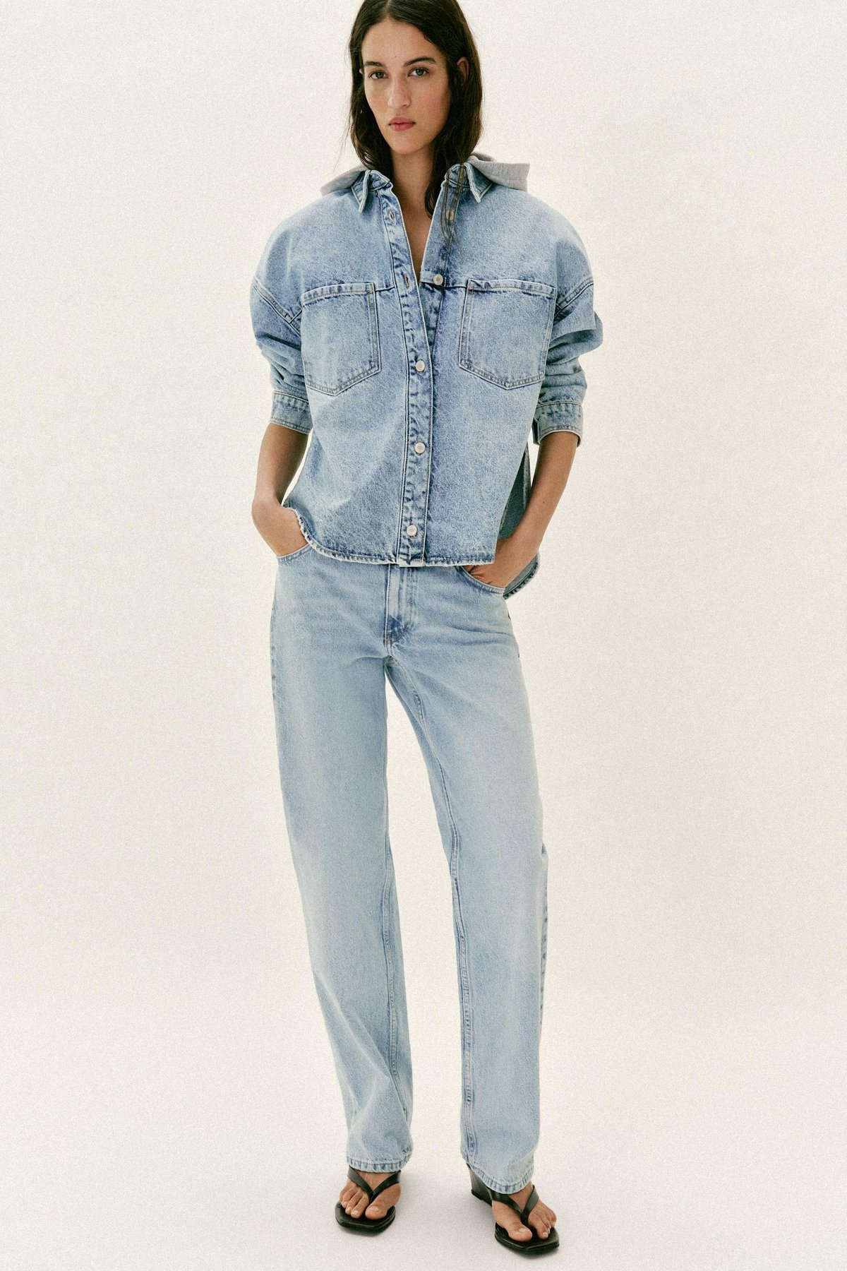 Light-wash denim shirt-jacket with a grey jersey hood, flat lay, front view, buttoned closed.