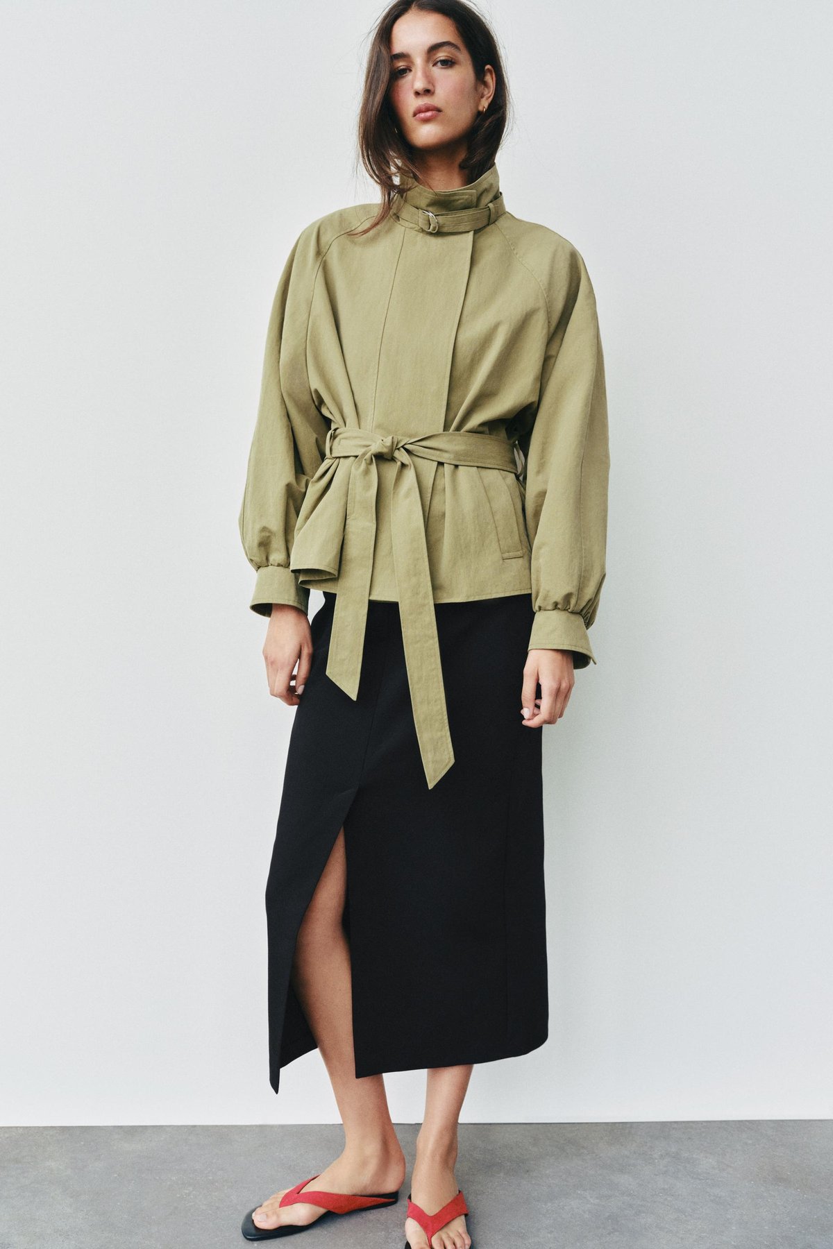 Sage-green belted jacket with a stand collar, flat lay, back view showing the pleated hem and tie belt.