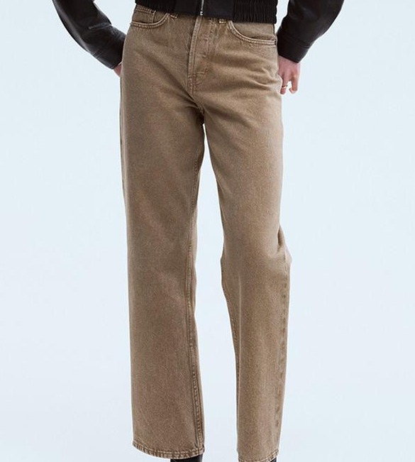 Back view of a woman wearing taupe straight-leg jeans and a black cropped leather jacket.