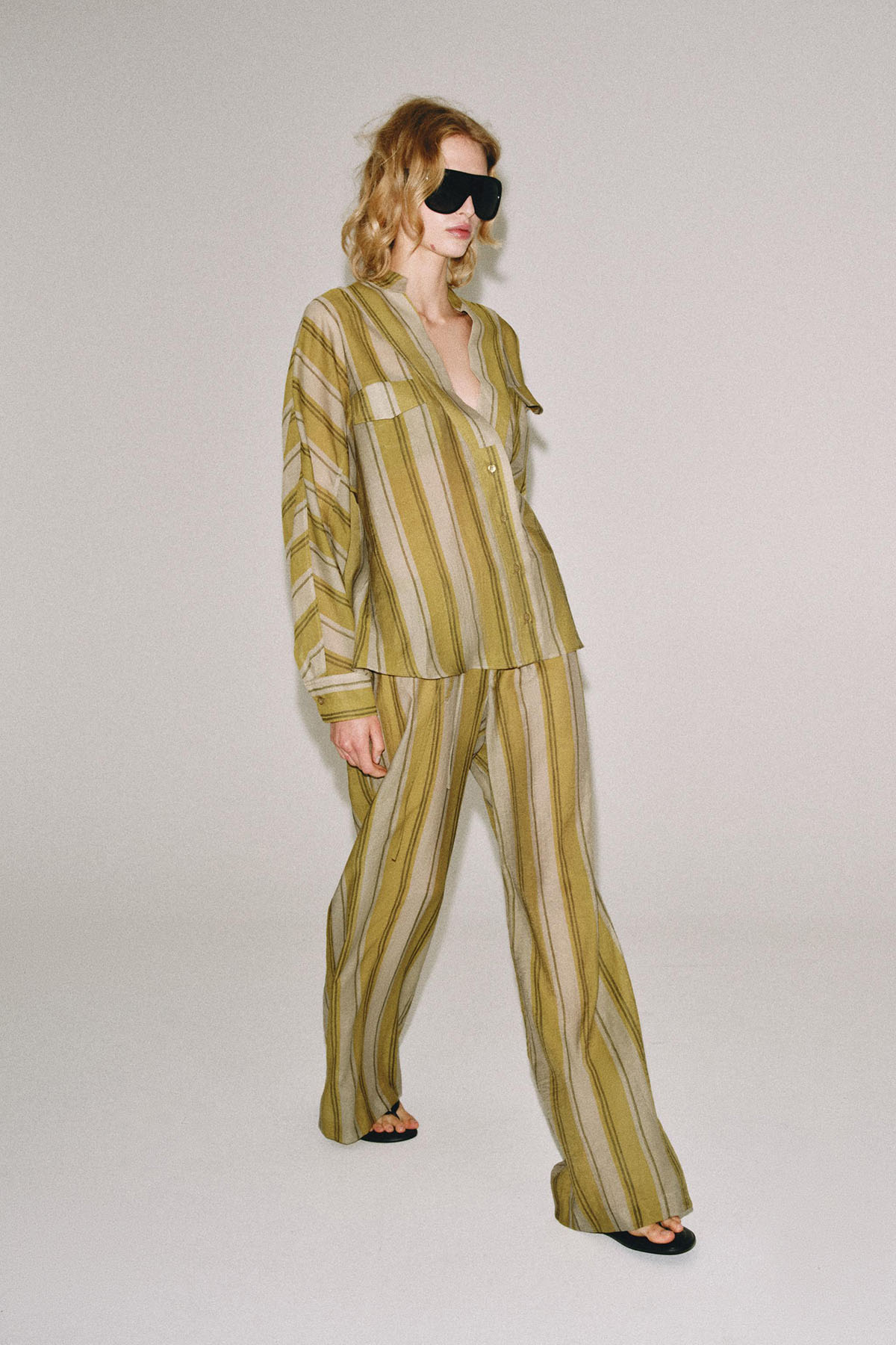 Woman wearing a relaxed striped shirt and trouser co-ord in olive and khaki tones
