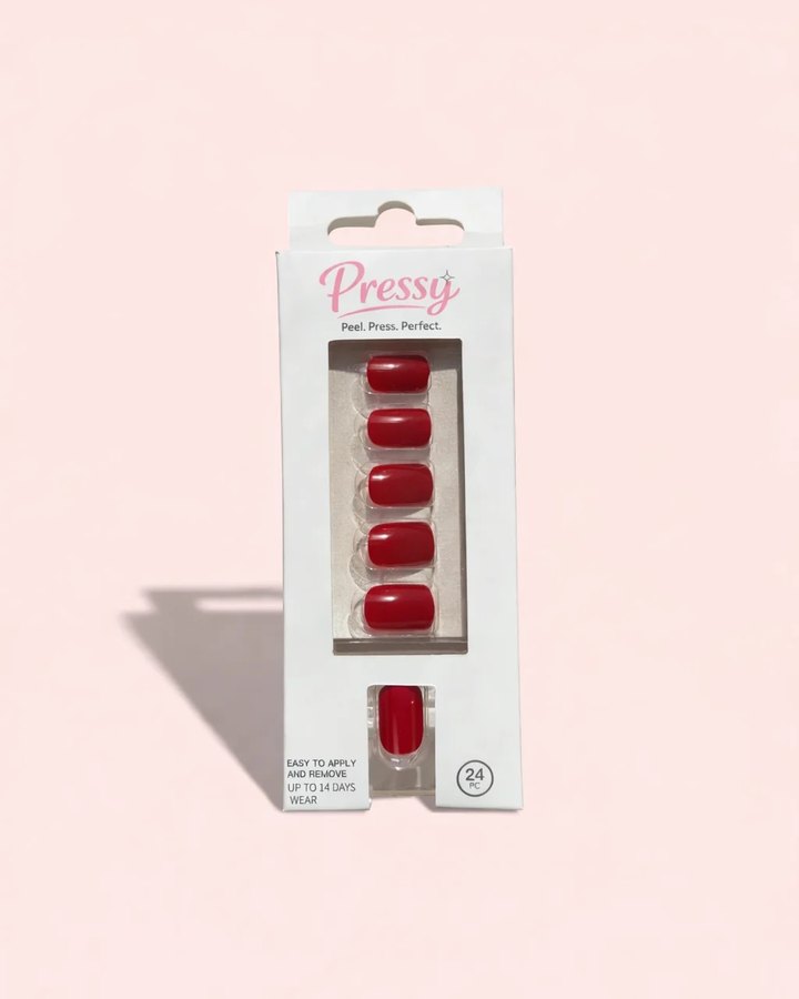 A pack of Pressy red gel press-on nails on a soft pink background